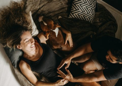 casal deitado no sofá do apartamento com seu cachorro